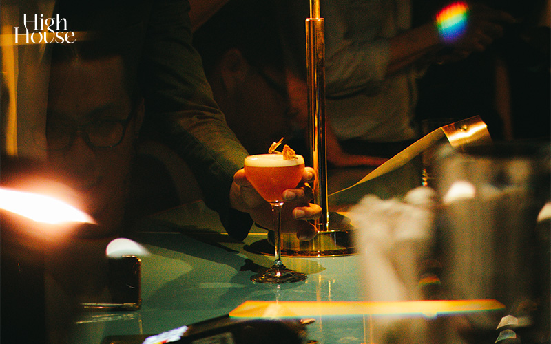 A bartender pouring a colorful cocktail into a glass.
