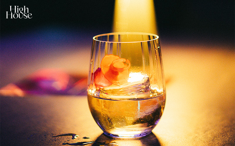 A fancy drink with a flower garnish on a bar.