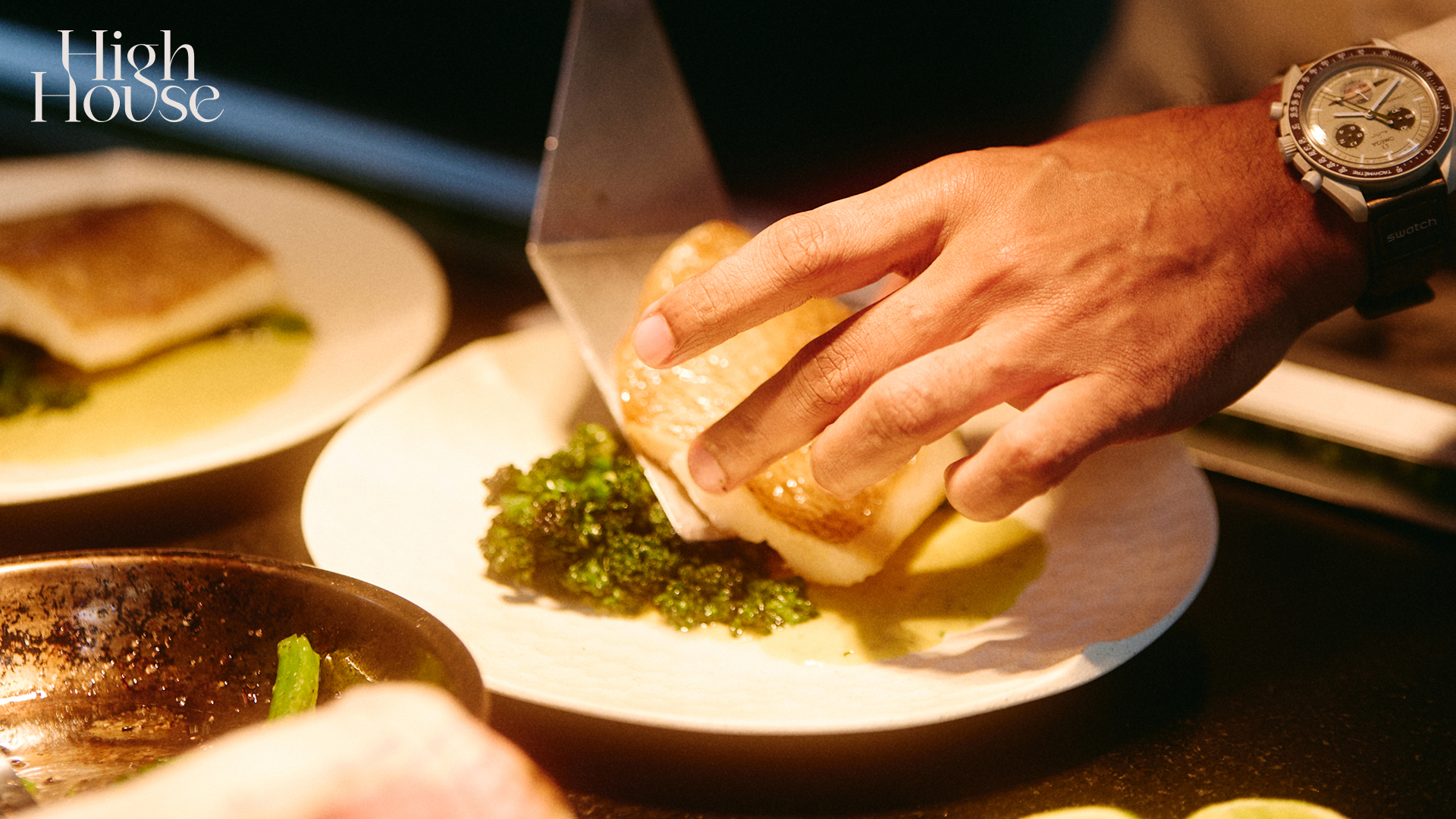 Chef carefully plating a fish dish in fine dining.